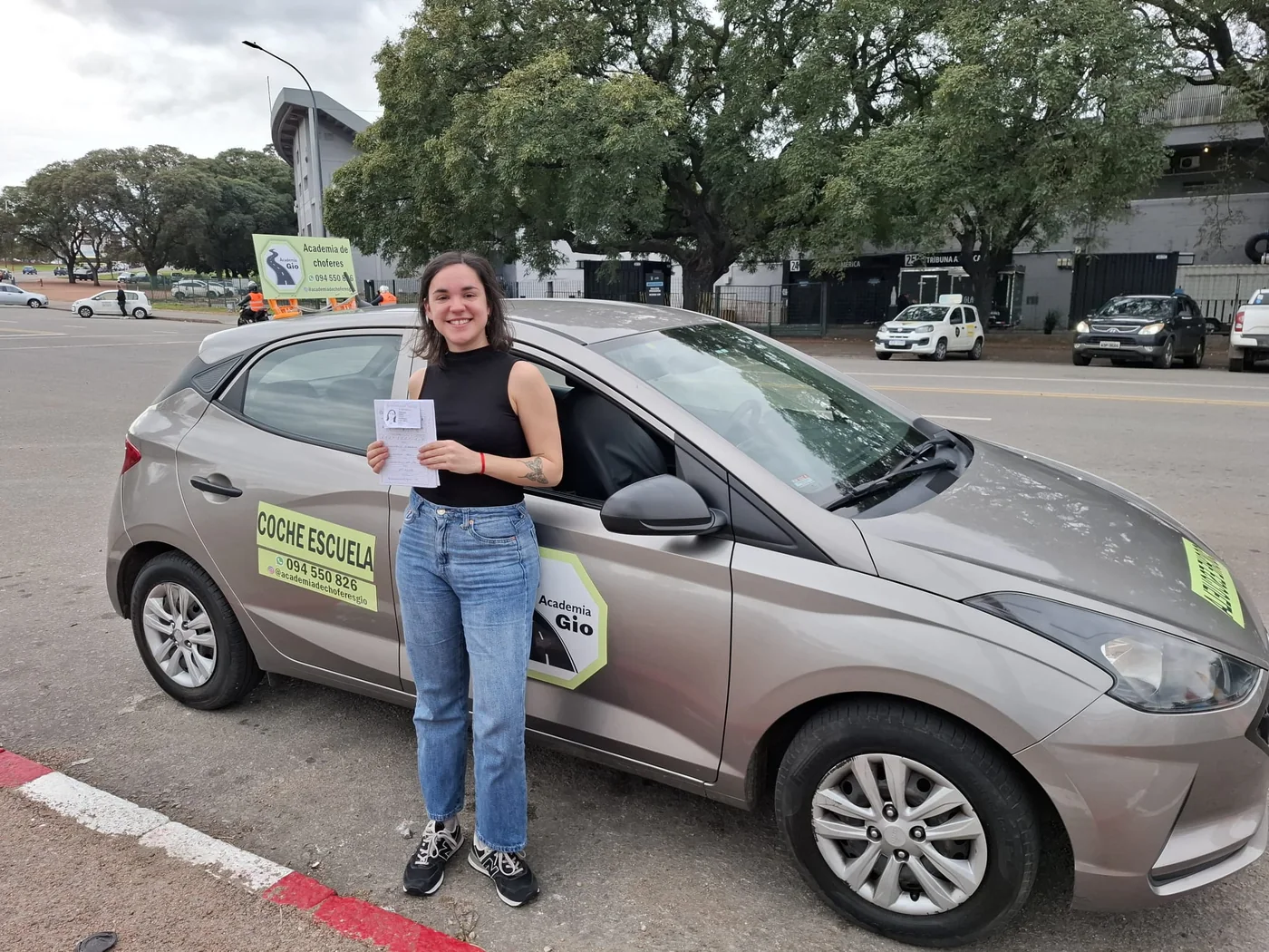 Alumna aprobada al lado del coche escuela
